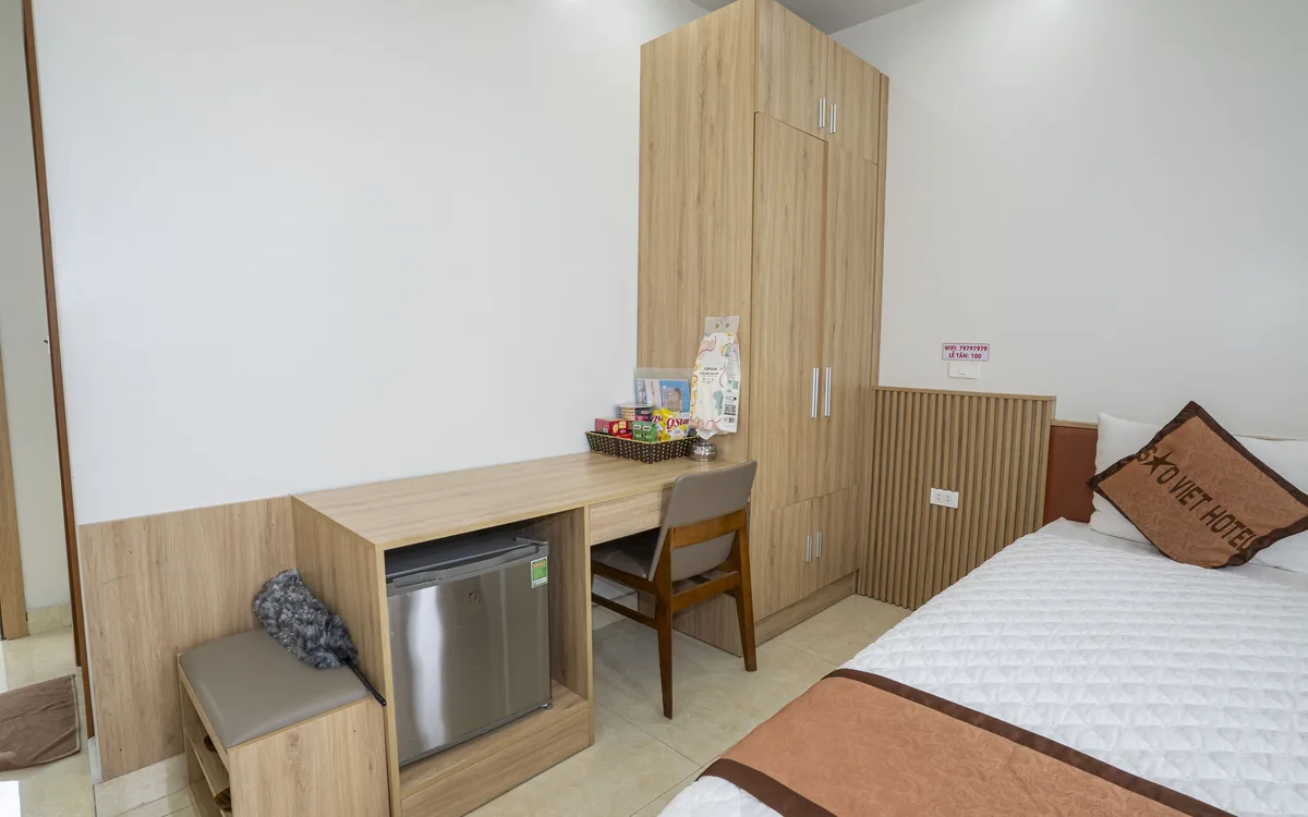 Góc bàn làm việc, ghế gỗ và tủ lạnh nhỏ cạnh giường đôi trong phòng Sao Việt Hotel