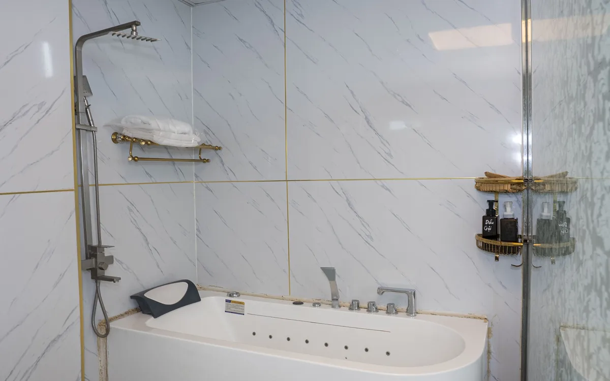 Phòng tắm riêng tại Sao Việt Hotel với bồn tắm nằm thư giãn, vòi sen và gạch vân đá trắng