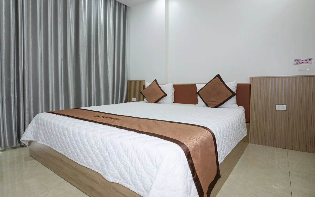 Các loại phòng trong khách sạn – phòng 1 giường đôi ga trắng, khăn trải giường nâu, sàn gạch sáng tại Sao Việt Hotel An Lão