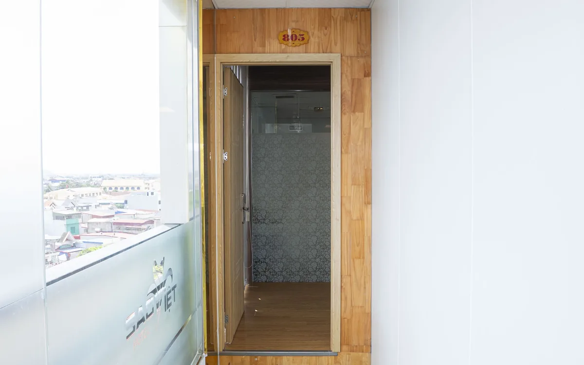 Cửa kính mờ in logo Sao Việt Hotel trong khung gỗ, mở vào lối phòng tắm sáng sủa