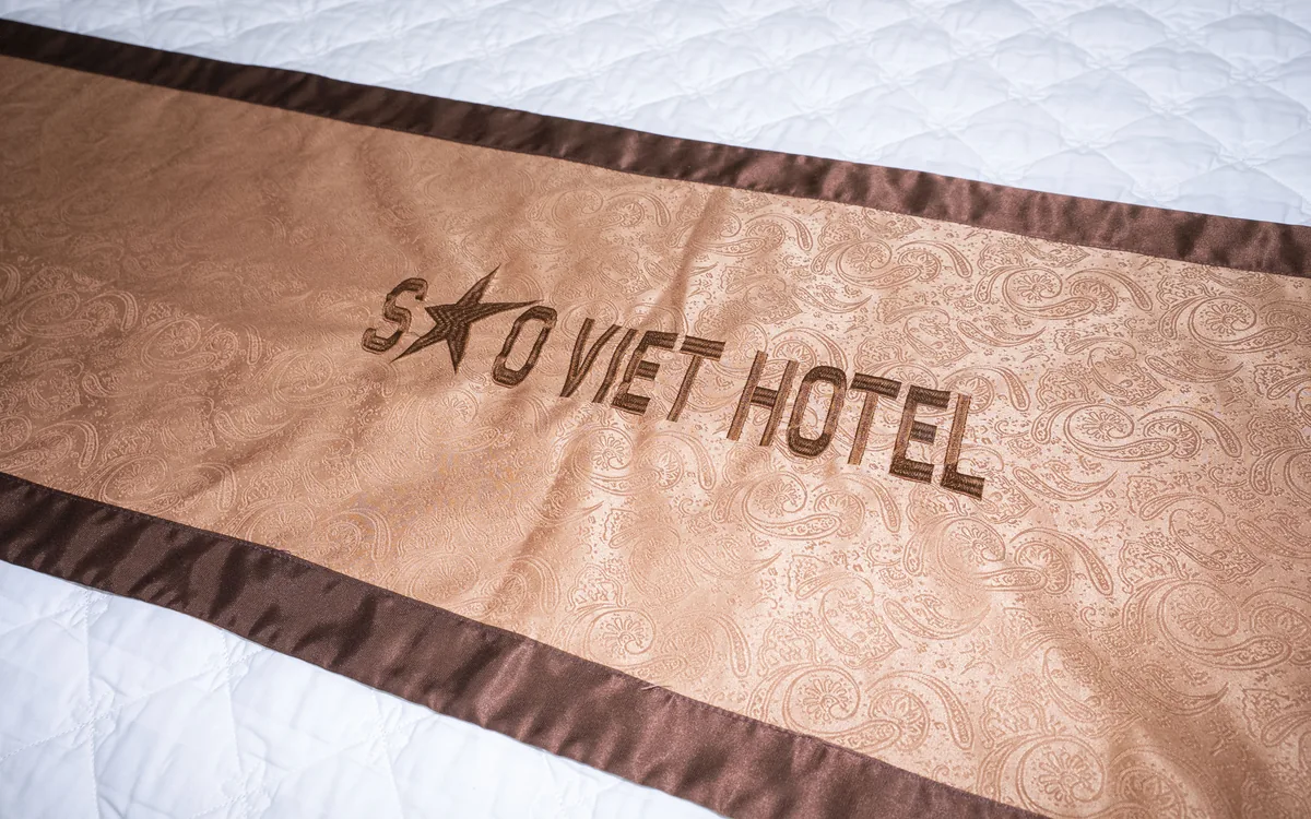 Cận cảnh khăn trải giường in chữ Sao Viet Hotel trên giường đôi