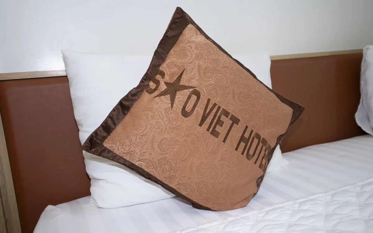 Gối in logo Sao Việt Hotel trên giường ga trắng – chi tiết phòng nghỉ tại An Lão