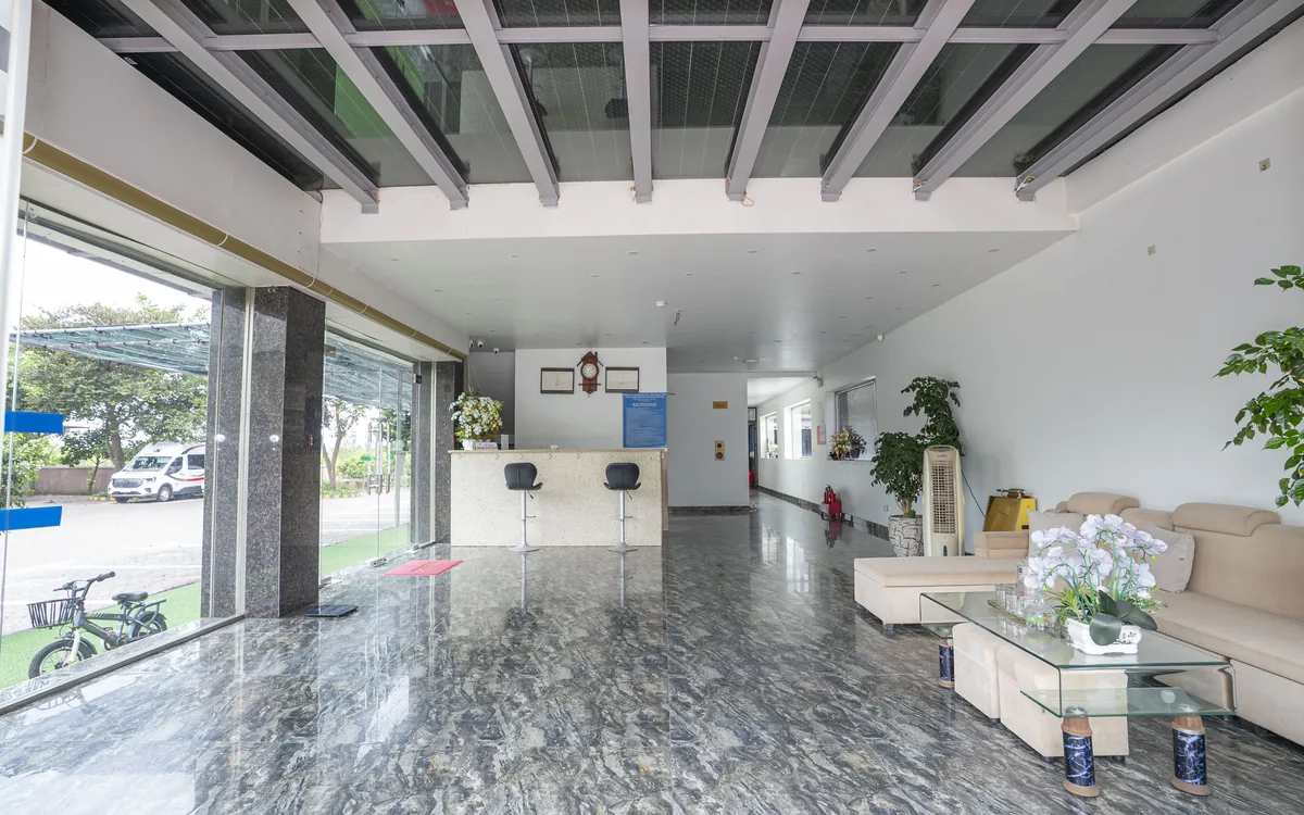 Khách sạn mở cửa 24/24 An Lão – sảnh sàn đá với quầy lễ tân, hai ghế bar, đồng hồ treo tường và bộ sofa be tại Sao Việt Hotel