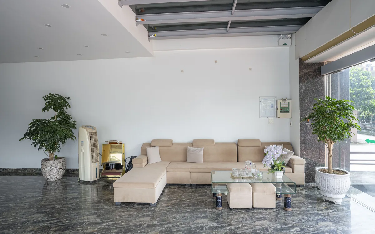 Bộ sofa be và bàn kính ở khu tiếp khách sảnh tầng trệt Sao Việt Hotel, cạnh cây xanh