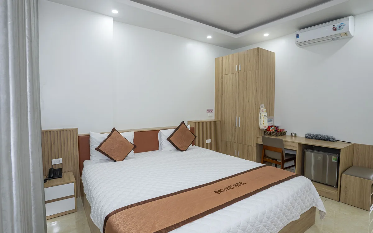Phòng 1 giường đôi lớn ga trắng, tủ gỗ và bàn làm việc tại Sao Việt Hotel An Lão