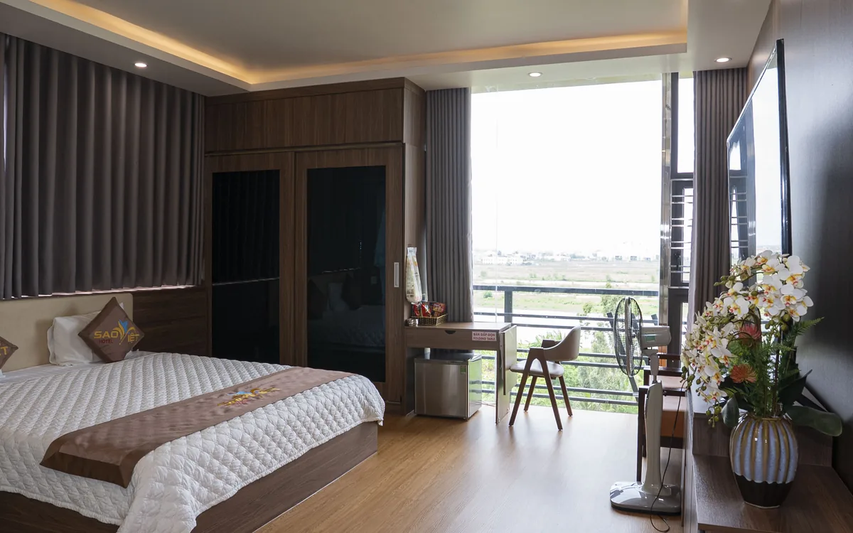 Phòng ốp gỗ tại Sao Việt Hotel An Lão với giường đôi và cửa kính ra ban công nhìn về phía sông
