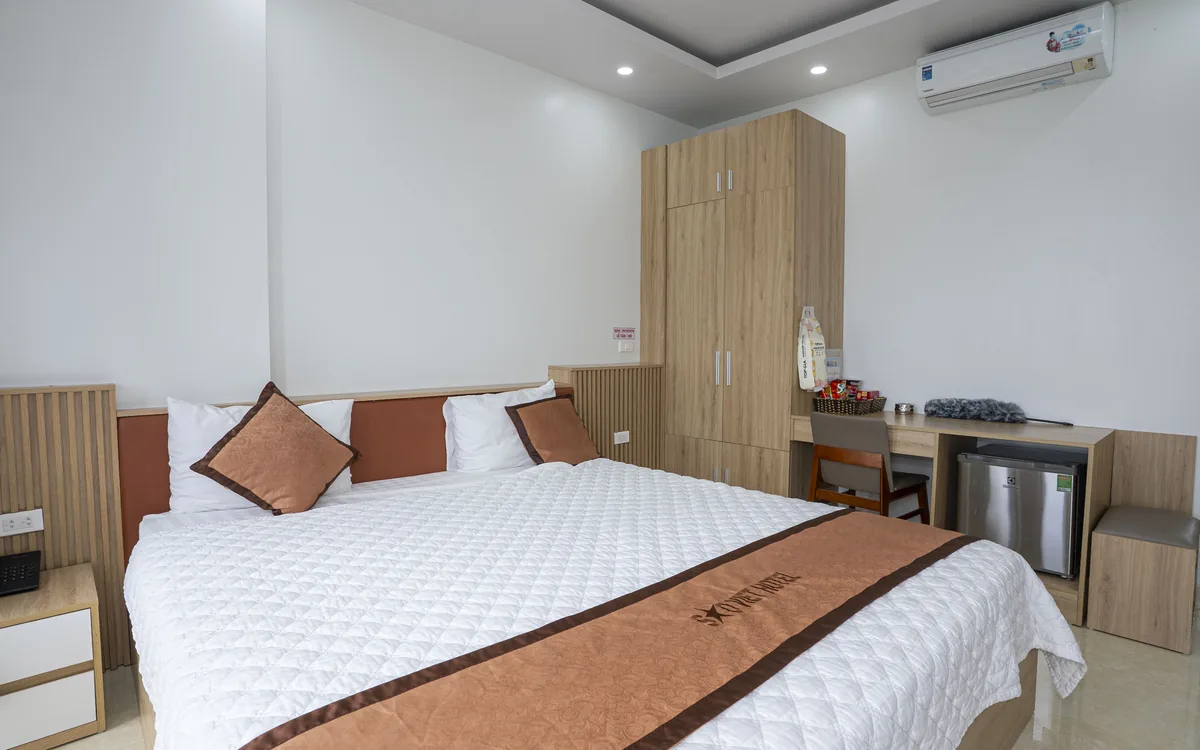 Phòng sáng với giường đôi lớn ga trắng, tủ gỗ cao và điều hoà tại Sao Việt Hotel An Lão