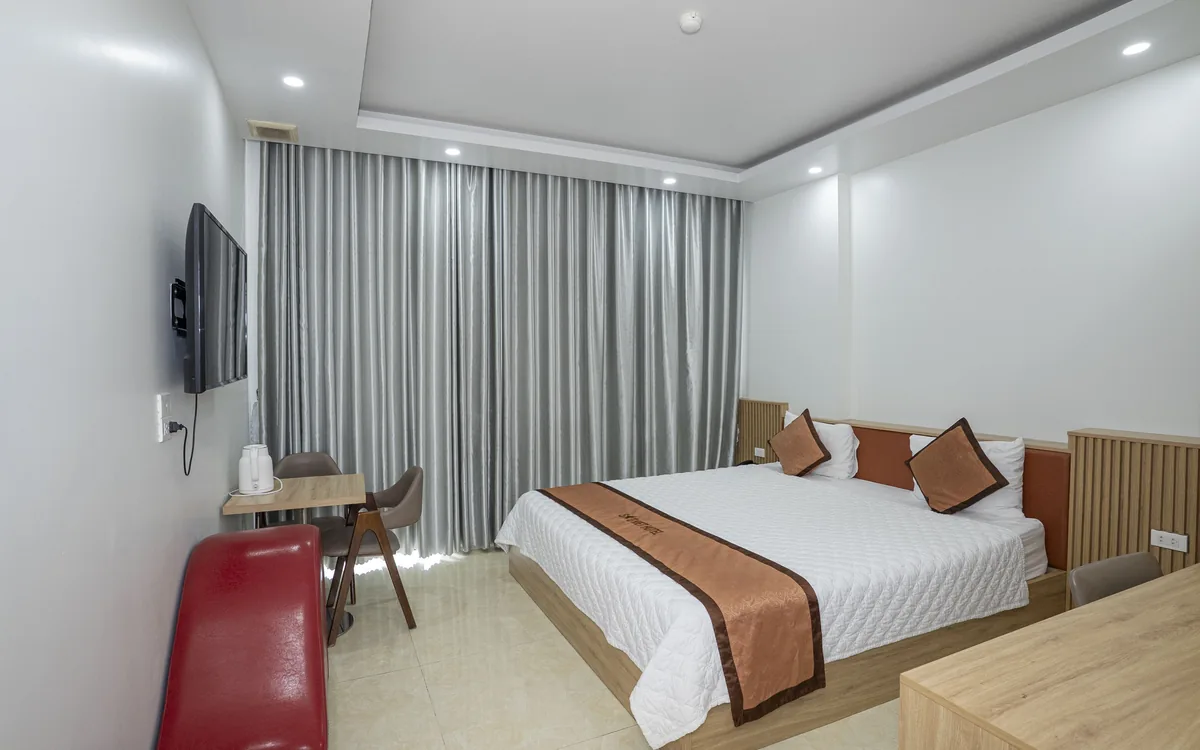 Phòng 1 giường đôi có TV treo tường, rèm xám và bàn nhỏ cho khách lẻ tại Sao Việt Hotel