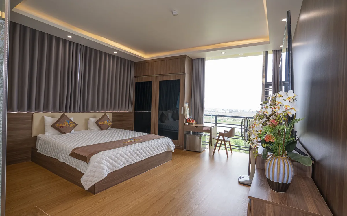 Phòng gỗ sàn gỗ tại Sao Việt Hotel với cửa kính lớn, ánh sáng tự nhiên và tầm nhìn cánh đồng xanh