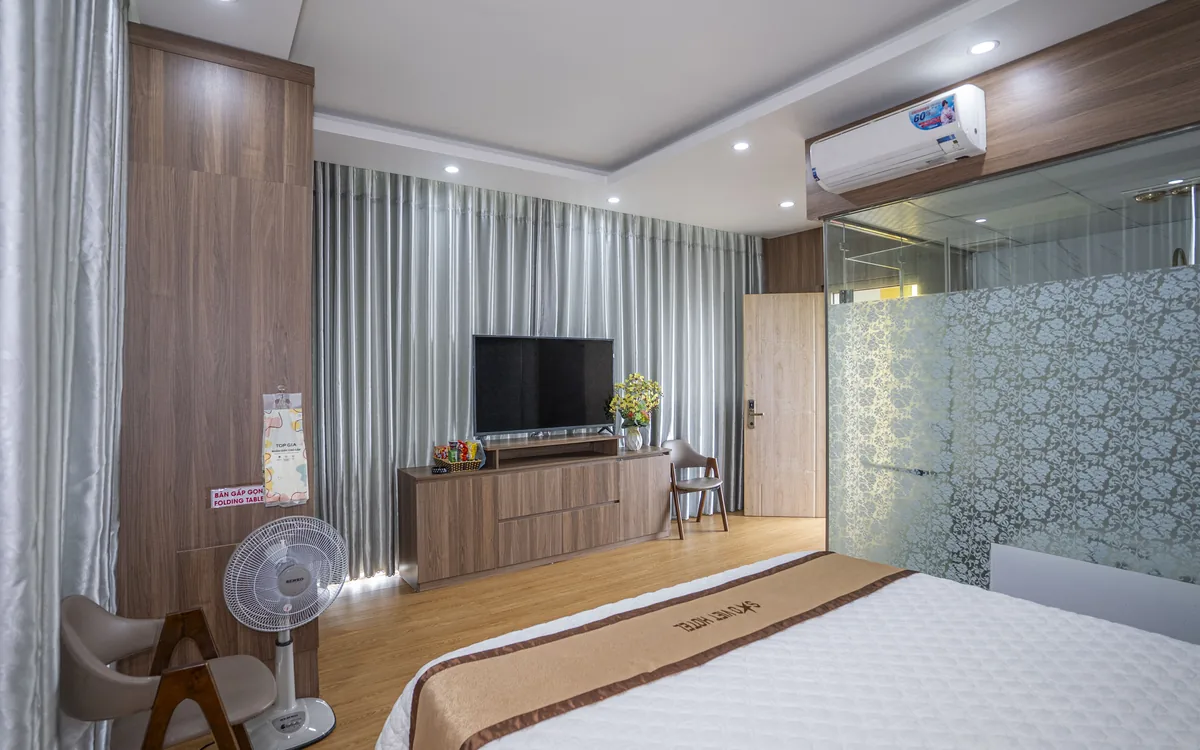 Phòng ốp gỗ có TV lớn, kệ gỗ, quạt cây và giường đôi tại Sao Việt Hotel An Lão