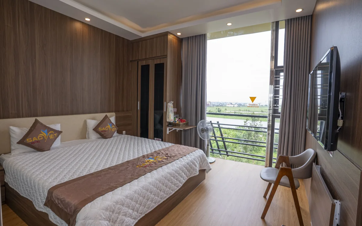 Phòng ốp gỗ tại Sao Việt Hotel với cửa kính lớn nhìn ra khoảng xanh thoáng mát