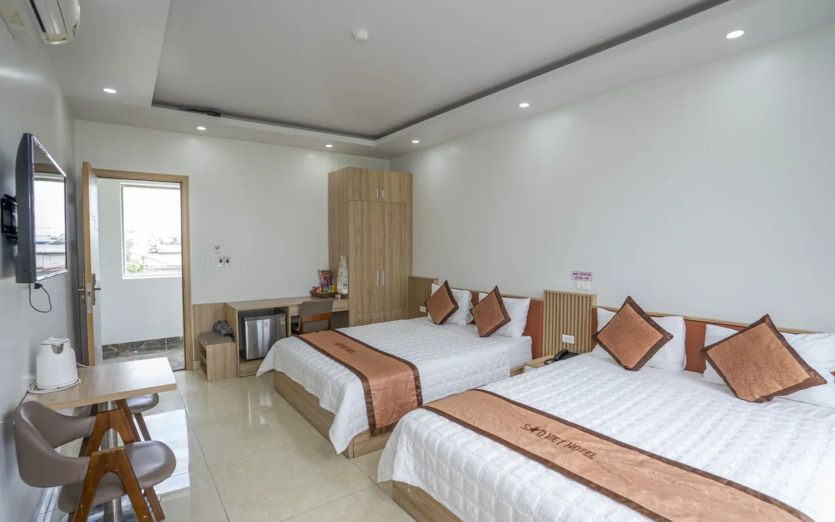 Phòng hai giường ga trắng tại Sao Việt Hotel với khăn trang trí logo, bàn ghế gỗ và TV treo tường
