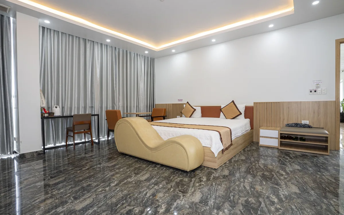 Phòng lớn sàn đá đèn hắt trần tại Sao Việt Hotel An Lão với giường đôi và ghế thư giãn