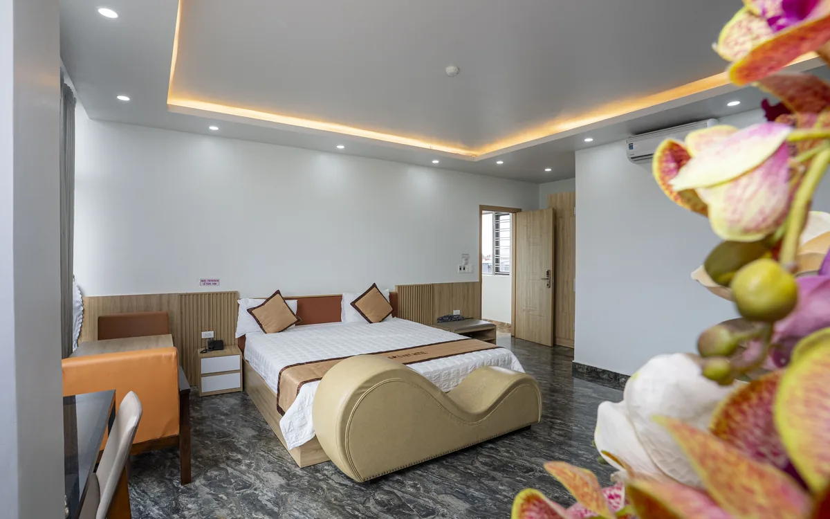 Phòng lớn sàn đá tối với giường đôi và ghế thư giãn màu be dáng cong tại Sao Việt Hotel An Lão