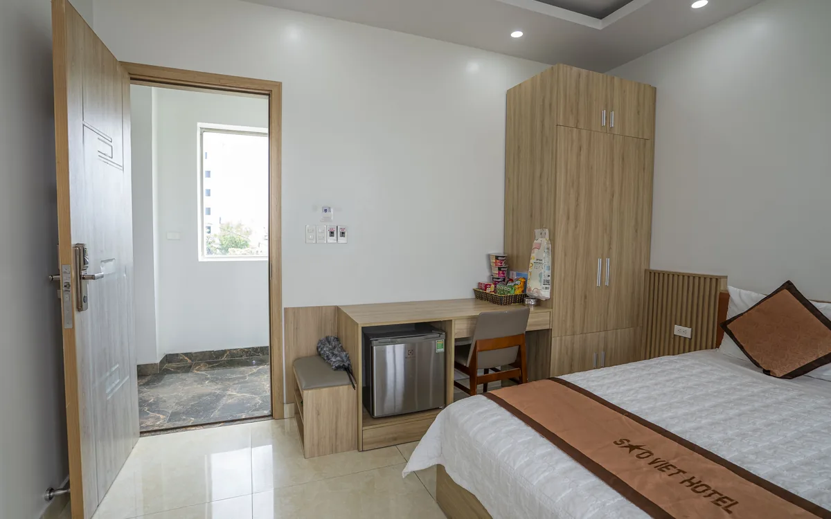 Phòng giường đôi nhìn từ cửa ra vào với tủ gỗ, minibar và bàn nhỏ tại Sao Việt Hotel