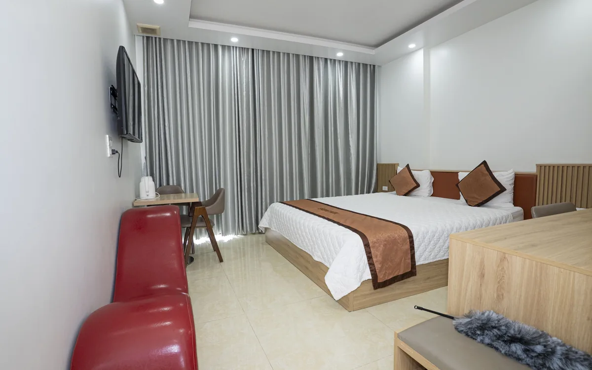 Phòng Standard ga trắng tại Sao Việt Hotel với TV, sofa đỏ và bàn làm việc nhỏ