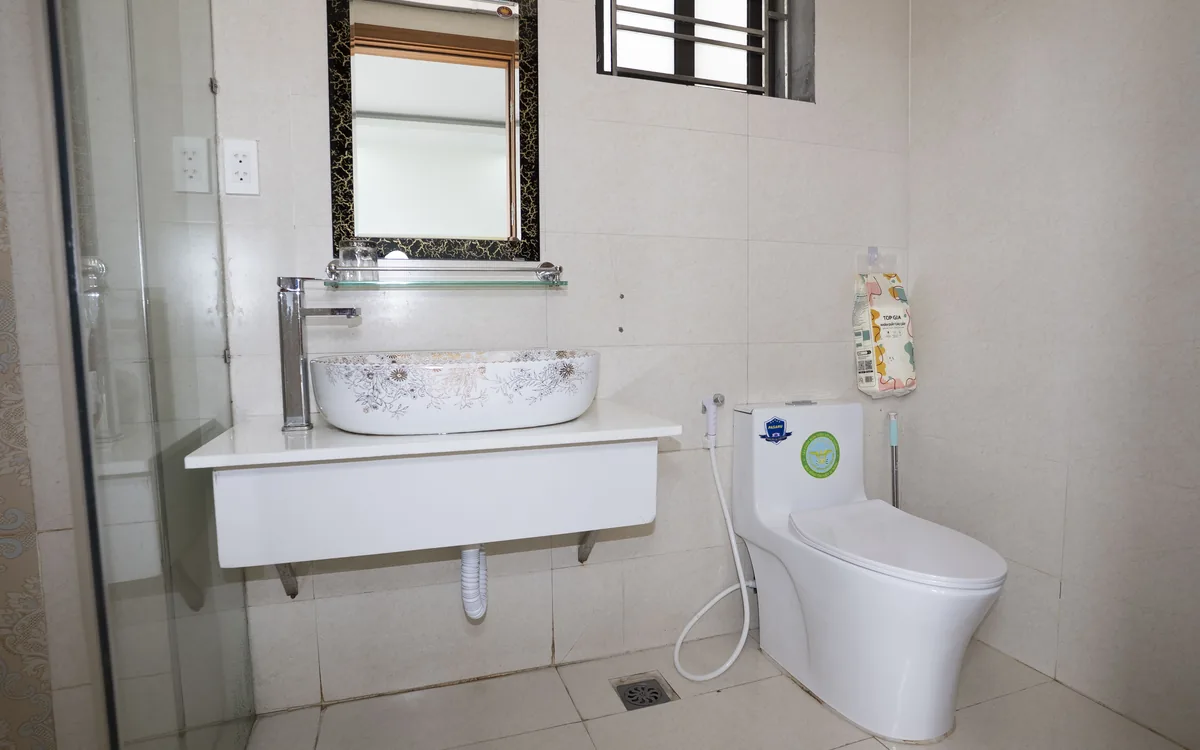 Phòng tắm hạng Deluxe ở An Lão – lavabo, gương, vòi sen vách kính, bồn cầu và vòi xịt tại Sao Việt Hotel