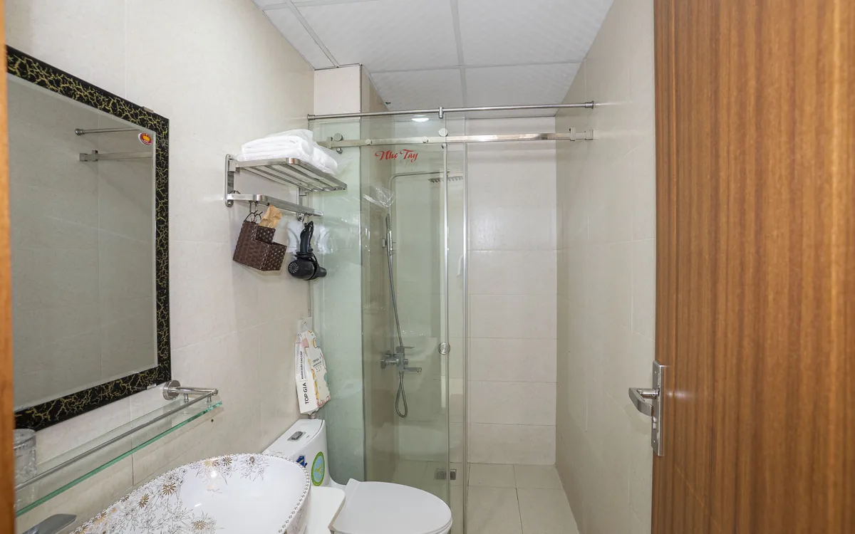 Phòng tắm trong phòng khách sạn ở An Lão – lavabo hoa văn, gương và vòi sen vách kính tại Sao Việt Hotel