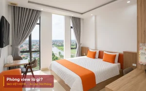 Phòng view là gì – ảnh minh hoạ phòng giường đôi nội thất gỗ có cửa kính lớn mở ra ban công, kèm tiêu đề bài viết