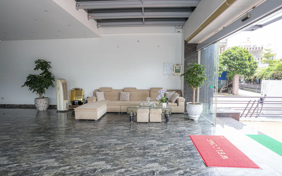 Khu tiếp khách ở sảnh tầng trệt Sao Việt Hotel với bộ sofa be, bàn kính, cây xanh và thảm Welcome