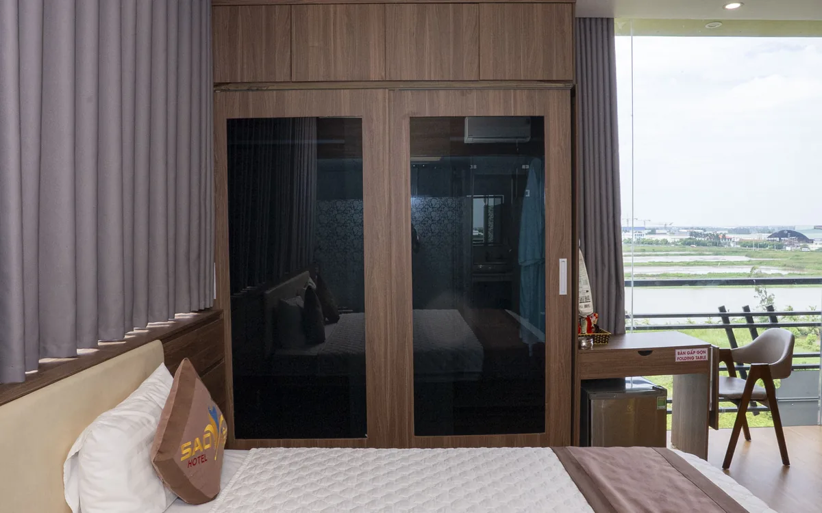 Tủ quần áo cửa kính đen và ban công nhìn ra cánh đồng trong phòng Sao Việt Hotel